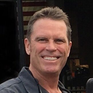 Smiling man with short hair outdoors.